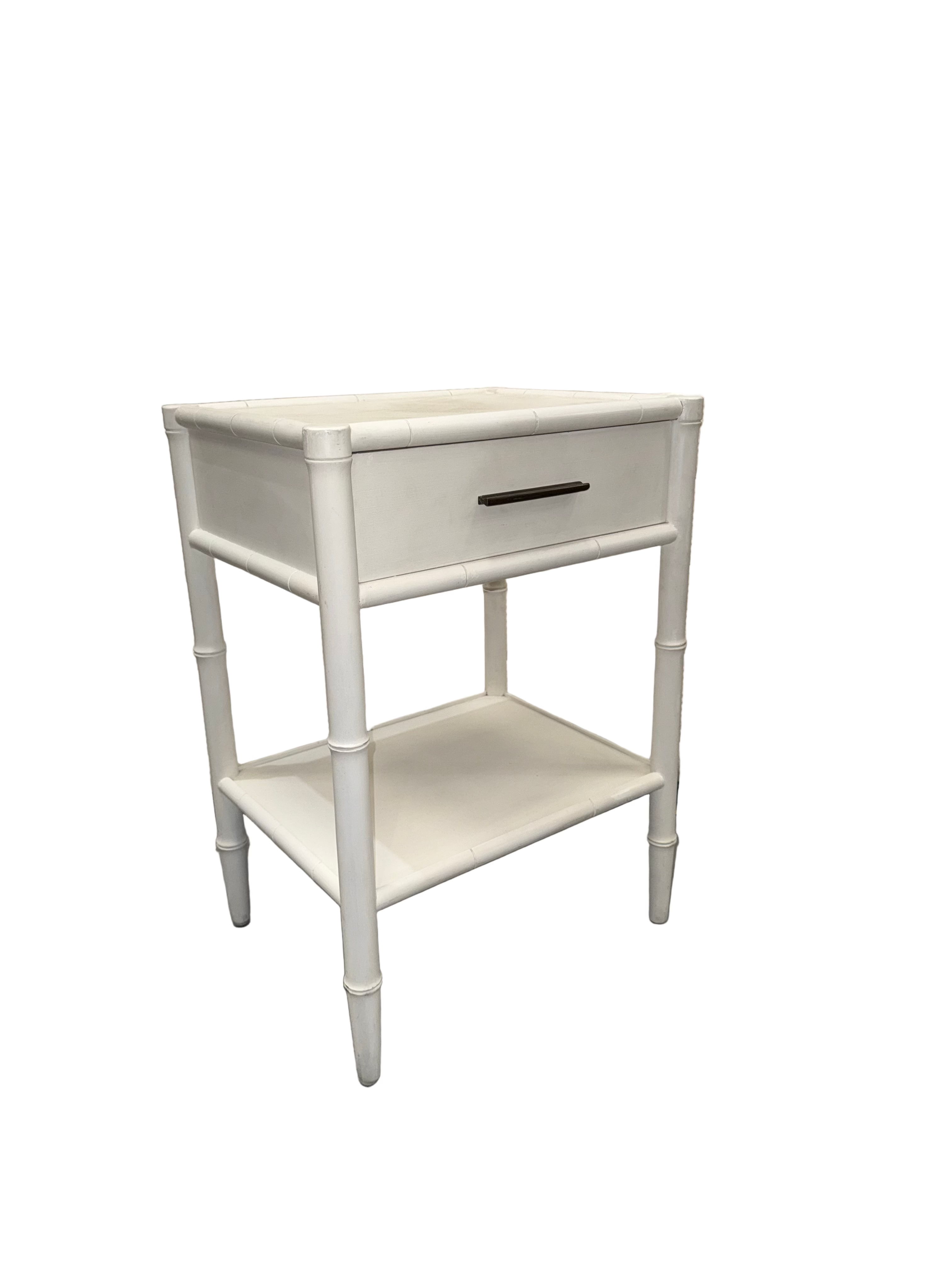 White nightstand with a single drawer in front of mattress samples